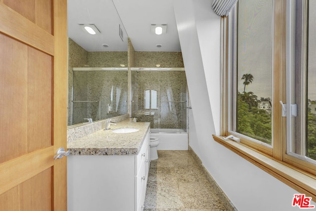 full bathroom featuring combined bath / shower with glass door, vanity, and toilet