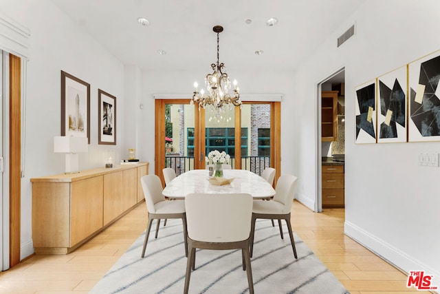 dining area with light hardwood / wood-style floors and an inviting chandelier