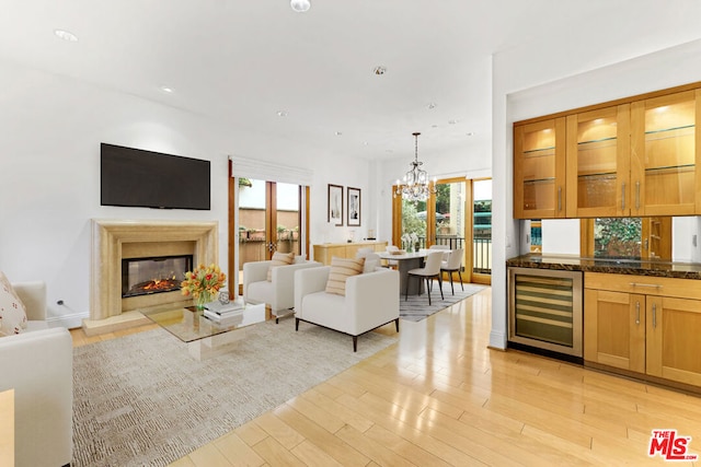 living room featuring a chandelier, light wood-type flooring, and wine cooler