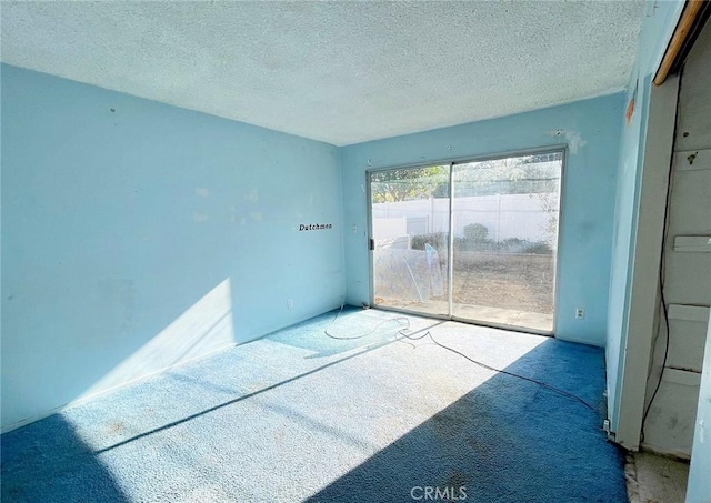 carpeted empty room with a textured ceiling