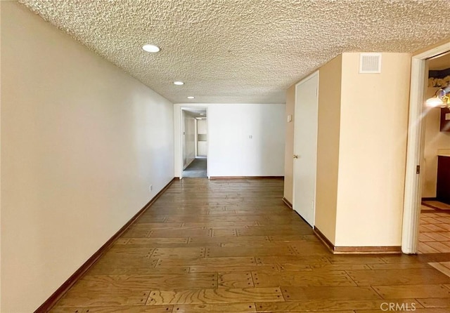 hall with wood-type flooring and a textured ceiling