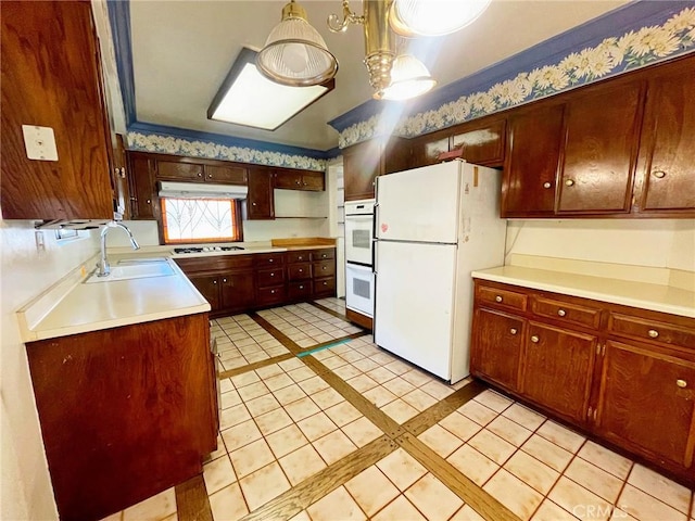 kitchen featuring pendant lighting, white appliances, light tile patterned floors, and sink