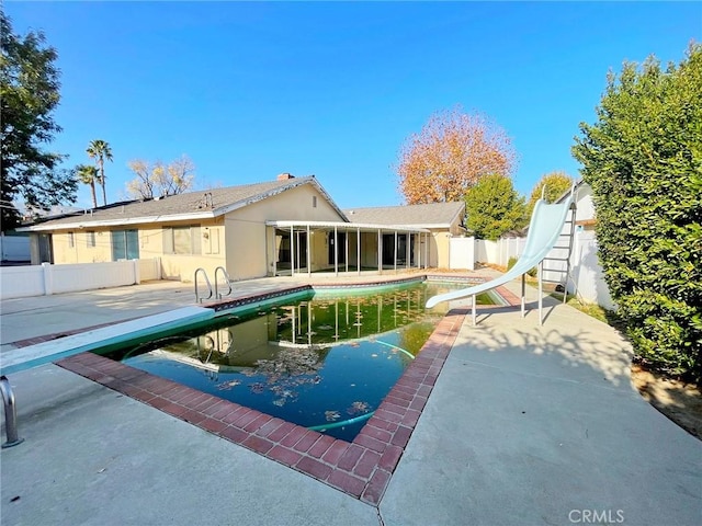 rear view of house with a fenced in pool, a patio area, and a sunroom