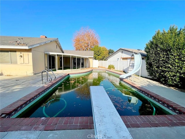 view of pool featuring a patio area, a diving board, and a water slide