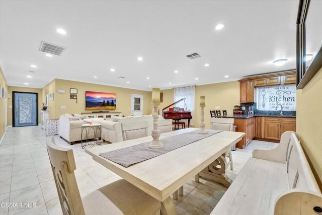 dining area with sink, light tile patterned floors, and ornamental molding