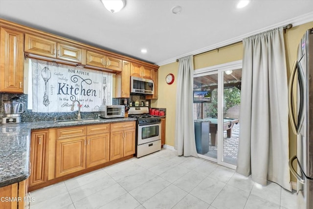 kitchen with appliances with stainless steel finishes, tasteful backsplash, dark stone counters, and sink