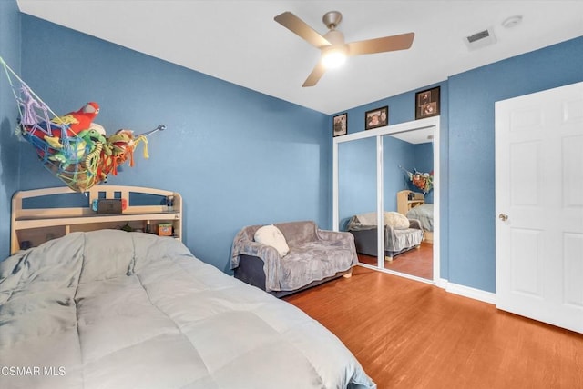 bedroom with ceiling fan, wood-type flooring, and a closet