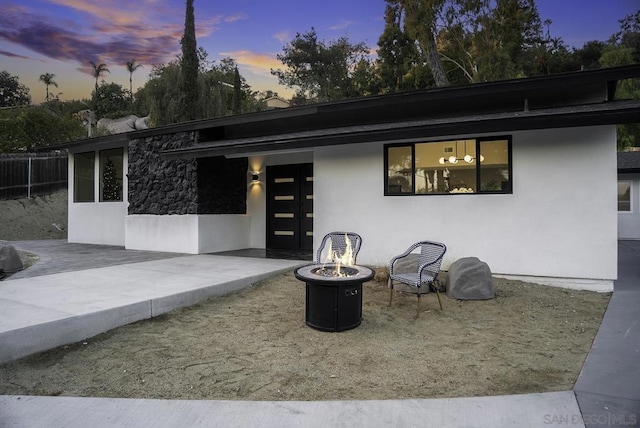 back house at dusk with a patio area and a fire pit