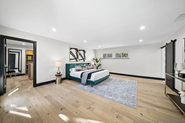 bedroom with light hardwood / wood-style floors and a barn door