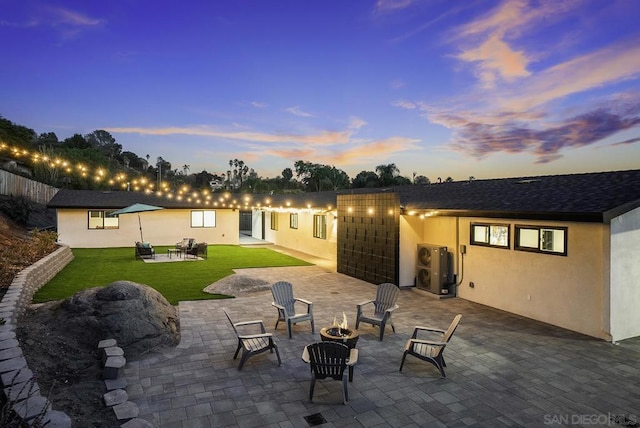 patio terrace at dusk with a fire pit and a lawn