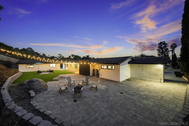 patio terrace at dusk with a lawn and an outdoor fire pit