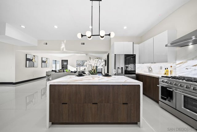 kitchen featuring appliances with stainless steel finishes, white cabinets, hanging light fixtures, a center island, and dark brown cabinets