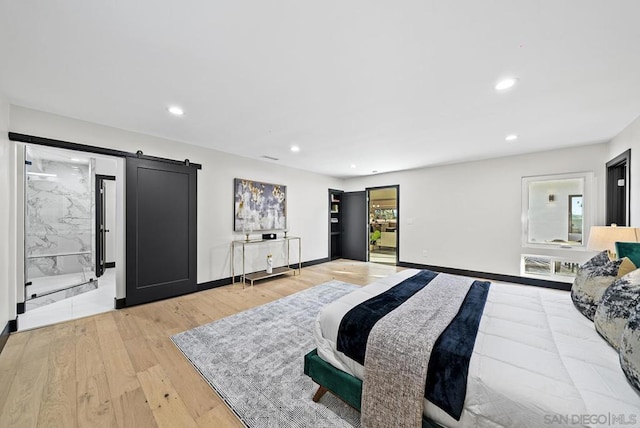 bedroom featuring multiple windows, a barn door, and light wood-type flooring