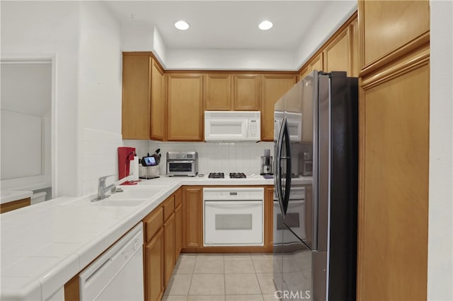 kitchen with decorative backsplash, sink, white appliances, tile counters, and light tile patterned floors