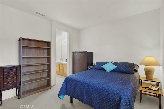 bedroom featuring ensuite bathroom and light colored carpet