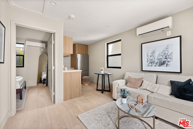 living room with light hardwood / wood-style floors and a wall unit AC