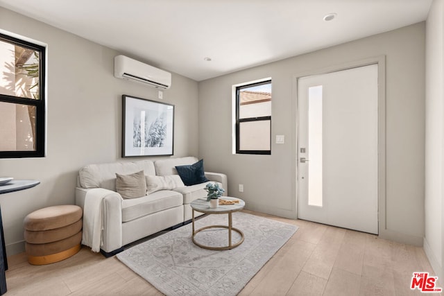 living room with plenty of natural light, light hardwood / wood-style floors, and a wall unit AC