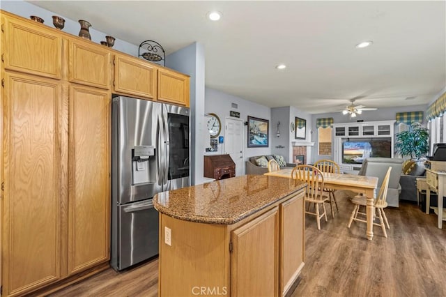 kitchen with hardwood / wood-style floors, a kitchen island, stainless steel refrigerator with ice dispenser, and stone counters