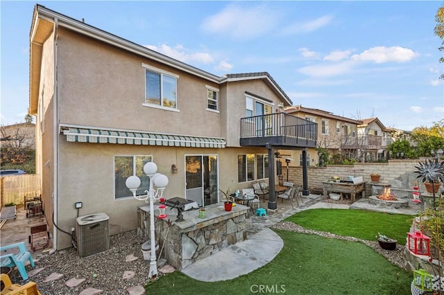 rear view of house featuring a balcony, a yard, a patio, and central air condition unit