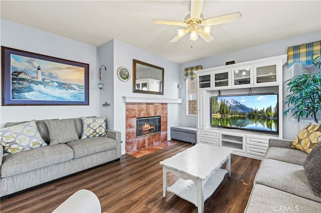 living room with a tile fireplace, dark hardwood / wood-style floors, and ceiling fan