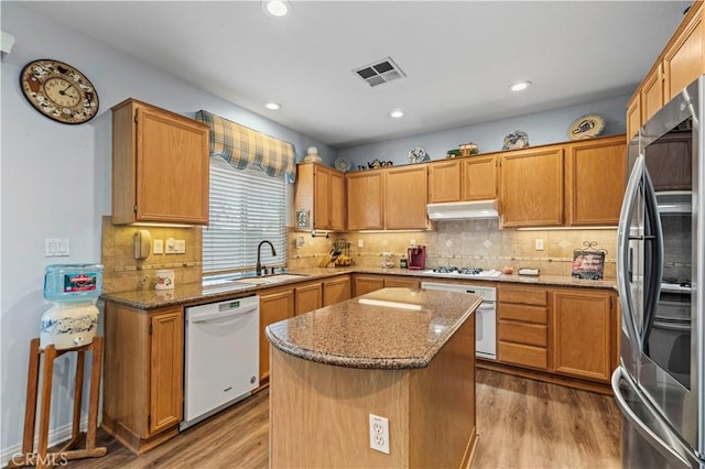 kitchen with light stone countertops, a center island, sink, light hardwood / wood-style flooring, and white appliances