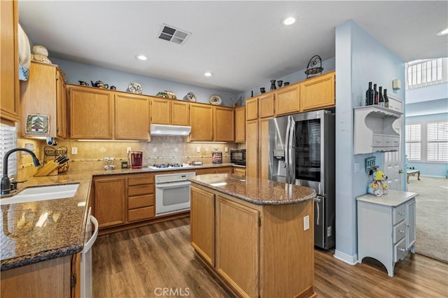 kitchen featuring white appliances, dark hardwood / wood-style floors, a kitchen island, and sink