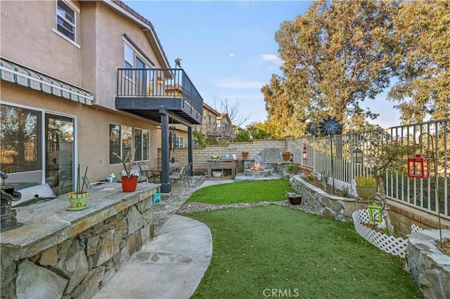 view of yard featuring a patio, a balcony, and an outdoor fire pit