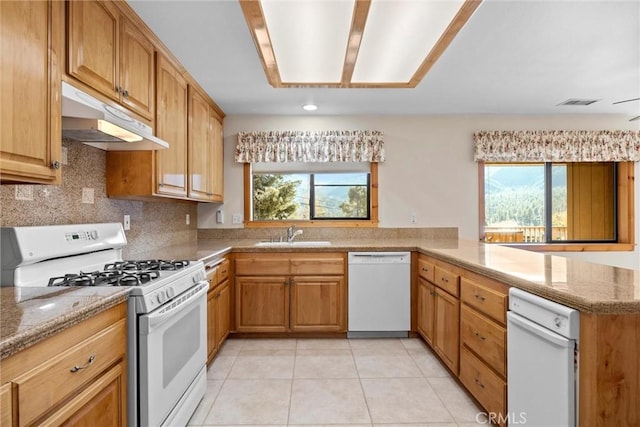 kitchen with a healthy amount of sunlight, sink, white appliances, and kitchen peninsula