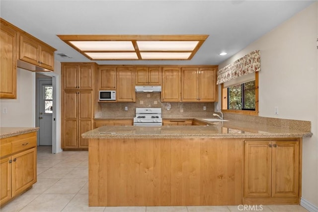 kitchen with light stone countertops, sink, tasteful backsplash, kitchen peninsula, and white appliances