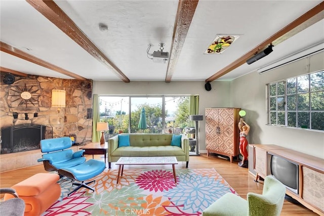 living room featuring beamed ceiling, light wood-type flooring, and a stone fireplace