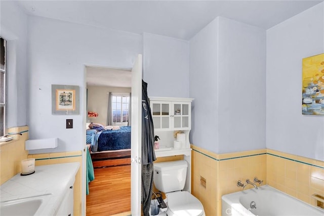 bathroom featuring a bath, hardwood / wood-style flooring, toilet, and sink