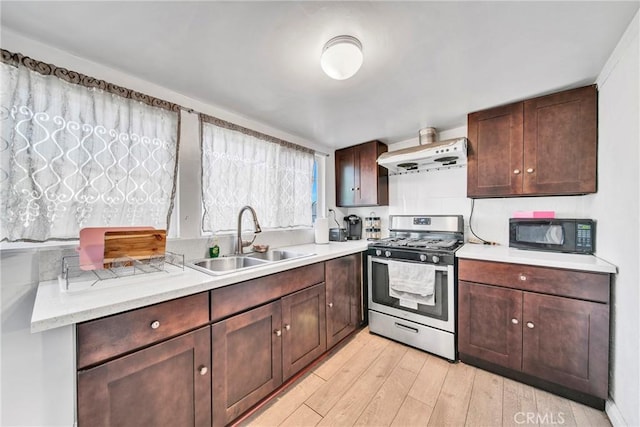 kitchen featuring light hardwood / wood-style flooring, dark brown cabinetry, range hood, gas range, and sink