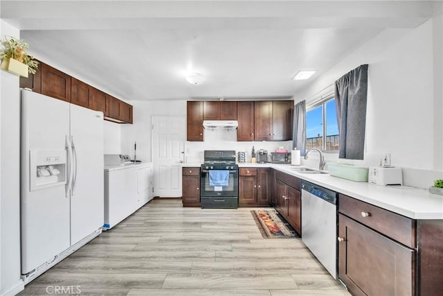 kitchen with black gas range, white refrigerator with ice dispenser, washer and dryer, sink, and dishwasher