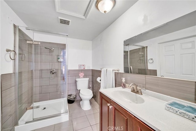 bathroom featuring tile patterned flooring, toilet, a shower with door, tile walls, and vanity