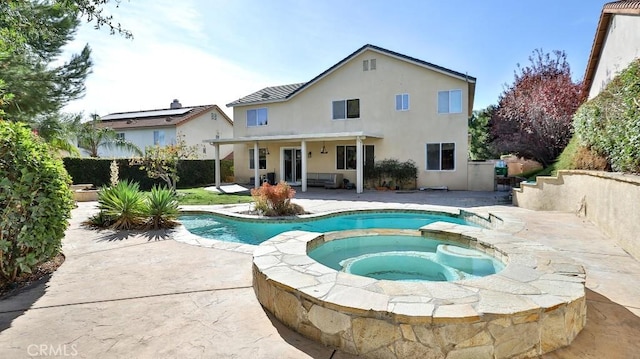 rear view of house with a swimming pool with hot tub and a patio area