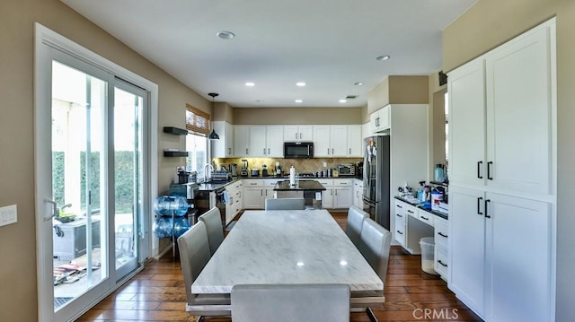 kitchen with decorative backsplash, appliances with stainless steel finishes, white cabinets, dark hardwood / wood-style floors, and a kitchen island