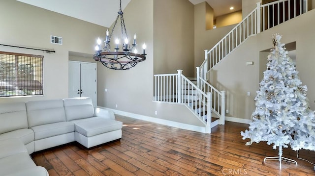 living room with high vaulted ceiling, dark wood-type flooring, and a notable chandelier