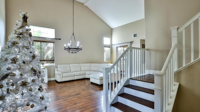 living room with high vaulted ceiling, dark wood-type flooring, and a notable chandelier