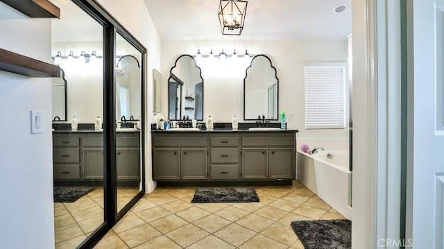 bathroom featuring tile patterned flooring, vanity, a notable chandelier, and a washtub