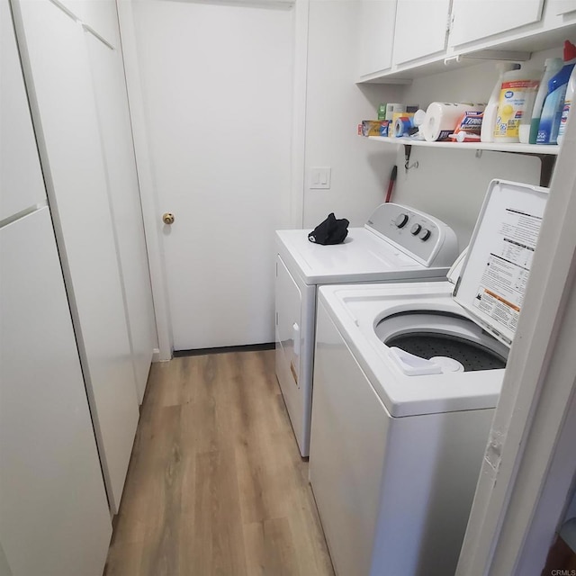 laundry room featuring cabinets, washer and clothes dryer, and light hardwood / wood-style floors