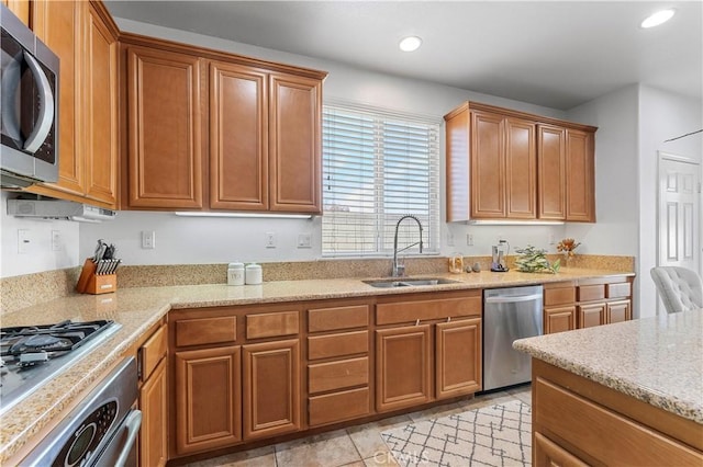 kitchen with light stone countertops, appliances with stainless steel finishes, light tile patterned floors, and sink