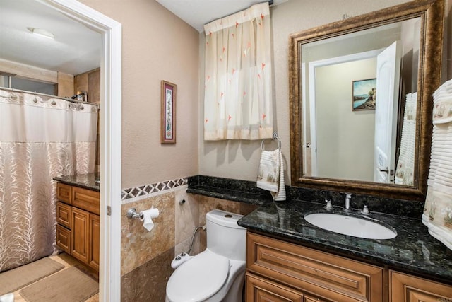 bathroom with vanity, toilet, and tile walls