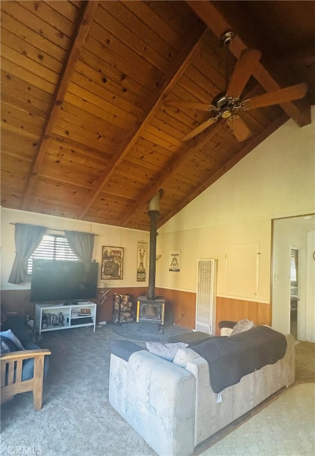 carpeted living room featuring beam ceiling, a wood stove, ceiling fan, high vaulted ceiling, and wood ceiling