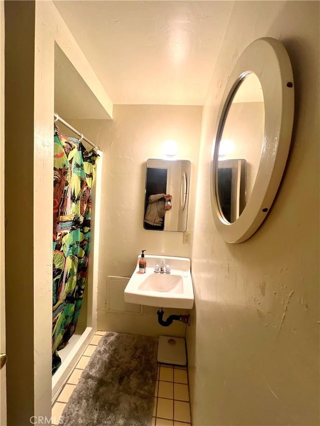 bathroom with tile patterned flooring, walk in shower, and sink