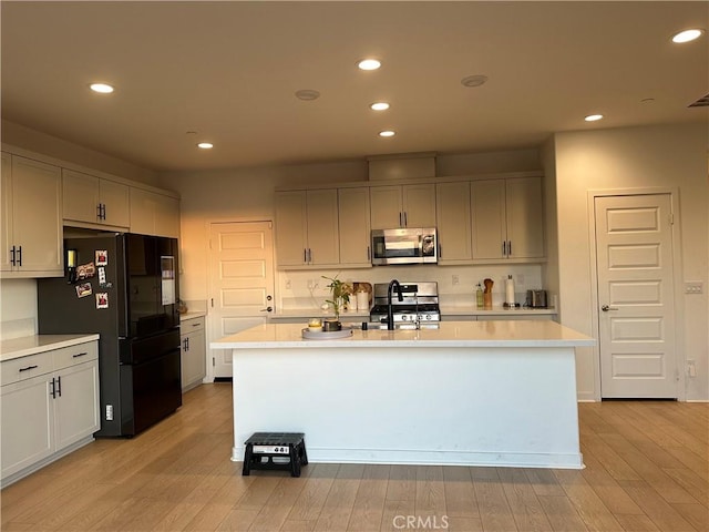 kitchen featuring an island with sink, stainless steel appliances, and light hardwood / wood-style floors