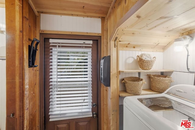 clothes washing area with washer / dryer, wooden ceiling, and wood walls