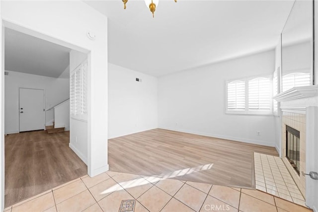 unfurnished living room with a tiled fireplace and light hardwood / wood-style flooring