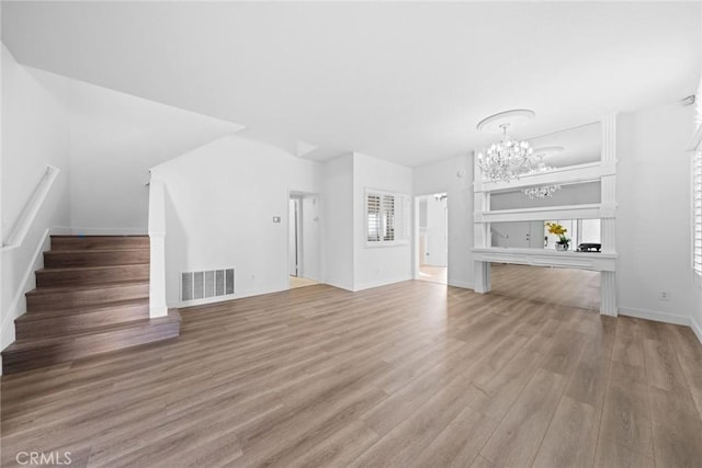 unfurnished living room with hardwood / wood-style flooring and an inviting chandelier