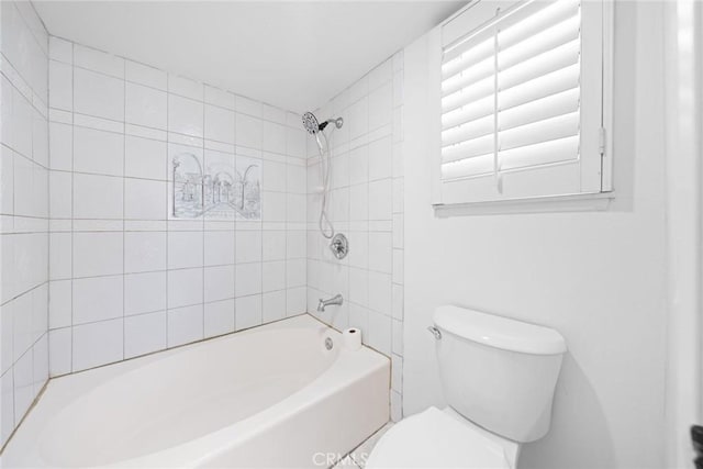 bathroom featuring tiled shower / bath combo and toilet