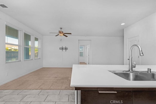 kitchen with dark brown cabinetry, light carpet, sink, and ceiling fan